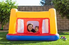 an inflatable bounce house with a woman and her child inside it on the grass