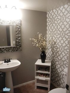 a white toilet sitting next to a sink in a bathroom under a mirror and light