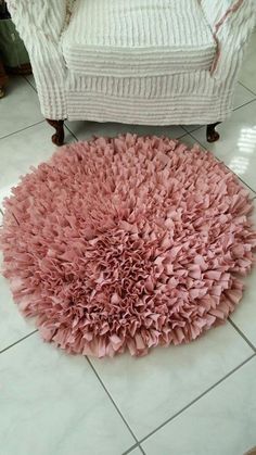 a pink rug sitting on top of a white tile floor next to a chair and ottoman