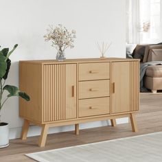 a wooden cabinet sitting on top of a hard wood floor next to a potted plant