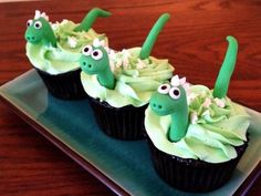 three cupcakes with green frosting and googly eyes sitting on a plate