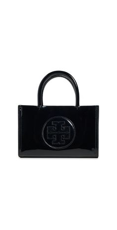 Find TORY BURCH Ella Bio Patent Mini Tote on Editorialist. The Tory Burch Ella Bio Patent Mini Tote is crafted from faux leather with a patent finish. It features a laser-cut logo emblem at the front, a structured silhouette, silver-tone hardware, and a magnetic closure. The interior includes a card slot and is lined with textile. The tote comes with an optional, adjustable strap. It measures 4.75 inches in height, 7.5 inches in length, and 2.25 inches in depth. The strap drop is 22 inches, and the handle drop is 3.25 inches. Tory Burch Ella, Tory Burch Tote, Classic American Style, Logo Emblem, Tory Burch Bag, Shell Crafts, Black Tote, Mini Tote, Black Bag