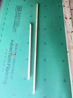 two pieces of wood sitting on top of a piece of green paper next to a pair of chopsticks