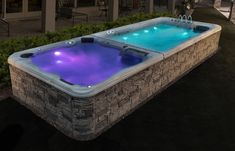 an outdoor hot tub lit up at night with blue lights on the sides and water running through it