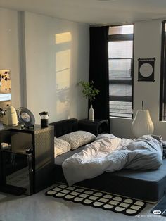 a bed sitting in the middle of a living room next to a window