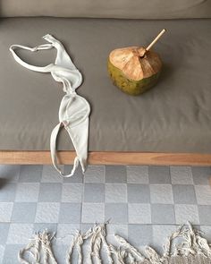 a white sculpture sitting on top of a gray couch next to a wooden table with an umbrella