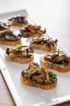 several pieces of bread topped with mushrooms on a white plate