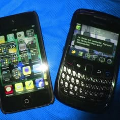 two cell phones sitting next to each other on a blue cloth covered surface with light shining through the screen