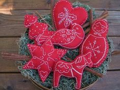 red felt christmas decorations in a basket on top of some green grass with cinnamon sticks