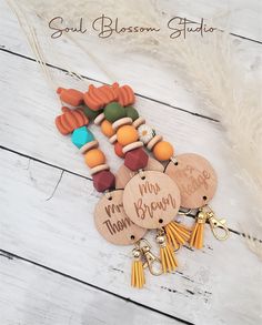 several wooden tags with tassels and charms attached to them on a white wood background