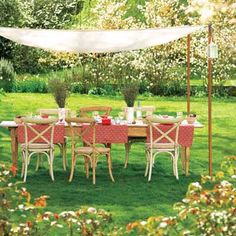 an outdoor dining table set up with pink chairs and white canopy in the middle of grass