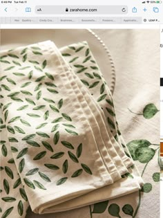 three napkins with green leaves on them sitting on top of a white table cloth