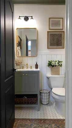 a white toilet sitting next to a bathroom sink under a mirror on top of a wall