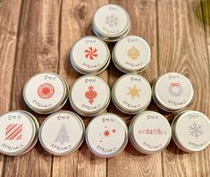 twelve tins with different designs on them sitting on a wooden table next to each other