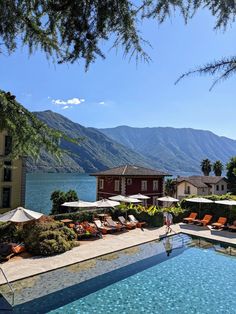 an outdoor swimming pool with chaise lounges and umbrellas next to the water