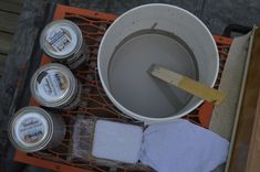 the bucket is full of paint and some cloths are next to it on an orange rack