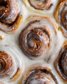 cinnamon rolls with icing sitting on top of each other in the middle of a pan