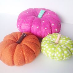 three different colored pumpkins sitting next to each other on a white counter top with polka dots