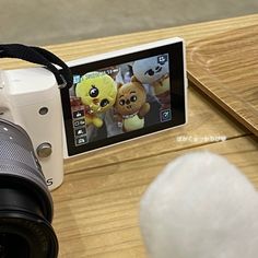 a digital camera sitting on top of a wooden table next to a cell phone with stuffed animals on it