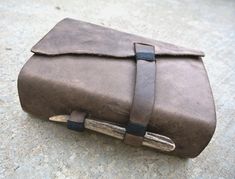 a brown leather case sitting on top of a cement floor