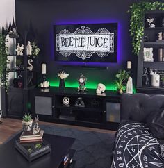 a living room with black furniture and green lighting on the tv screen that says beetlee juice