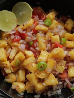 pineapple and onion salad in a black bowl with lime wedges on the side