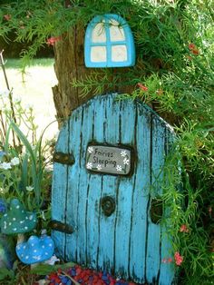 a blue fairy door sitting next to a tree