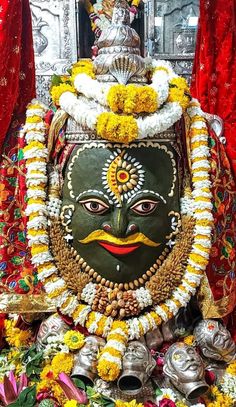 an idol is displayed in front of some red and yellow curtains with flowers on the floor