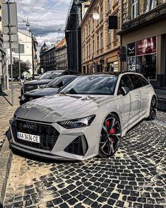 a white car parked on the side of a road next to other cars in front of buildings