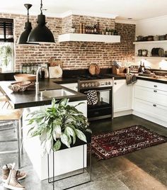 a kitchen with an oven, sink and potted plant on the counter top in front of a brick wall