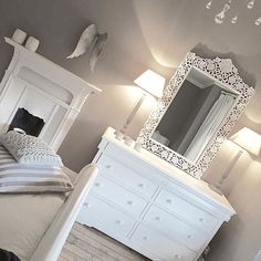 a white bed sitting under a mirror in a bedroom