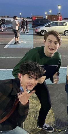 three young men standing next to each other in front of a parking lot at night