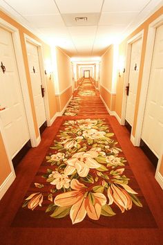 a long hallway with red carpeting and white doors leading to the rooms on either side