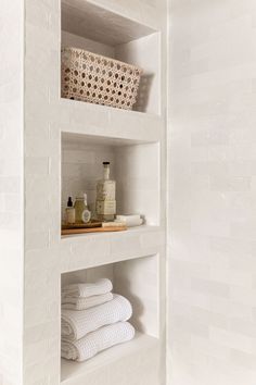 the shelves in the bathroom are filled with white towels and soaps on top of them