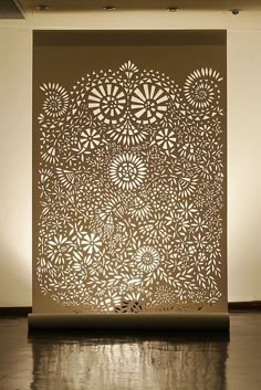 an intricate laser cut paper sculpture on display in a room with white walls and flooring