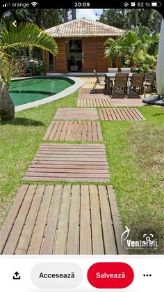 a wooden walkway leading to a pool in the middle of a yard with chairs and tables