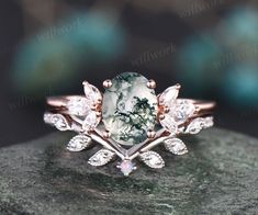 a close up view of a ring with an oval stone surrounded by leaves and diamonds