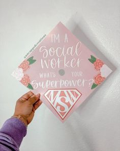 someone holding up a pink graduation cap with the words, i'm a social worker whats your super power?