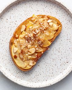 a piece of bread with almonds on it sitting on a white and beige plate