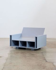 a blue bench sitting on top of a cement floor next to a white wall in an empty room