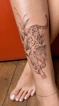 a woman's leg with a tattoo on it that has a leopard and flowers on it