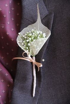 a boutonniere with baby's breath attached to the lapel of a suit