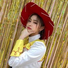 a woman wearing a red hat standing in front of some gold foil wallpaper and looking at the camera