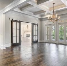 an empty living room with wood floors and french doors