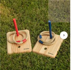 two wooden coasters with ropes on them sitting in the grass, one has a red and blue umbrella