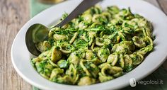 a white bowl filled with pasta covered in pesto