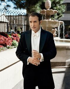 a man in a tuxedo standing next to a fountain