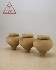 three wooden vases sitting next to each other on top of a table in front of a white wall