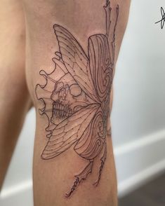 a woman's thigh with a butterfly and skull tattoo on the side by her