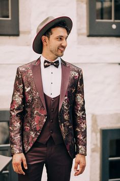 a man in a tuxedo and bow tie smiles at the camera while wearing a hat